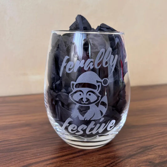Raccoon Christmas cocktail glass with “Ferally Festive” etched design - funny holiday drinkware for festive parties and unique seasonal gifting.